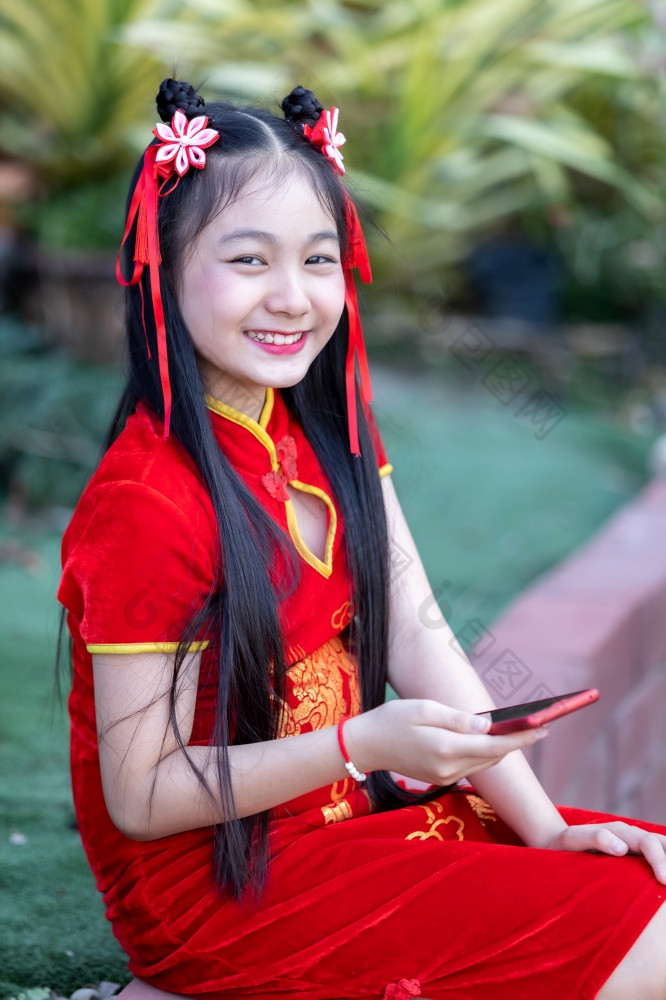 肖像美丽的微笑可爱的小亚洲女孩穿红色的传统的中国人旗袍装饰采取自拍与智能手机为中国人新一年节日中国人神社