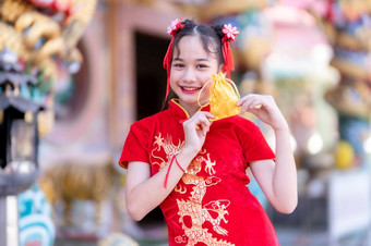 肖像美丽的微笑可爱的小亚洲女孩穿红色的传统的中国人旗袍装饰焦点显示金钱袋为中国人新一年节日中国人神社泰国