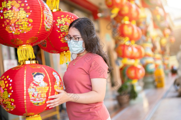 亚洲女人旅行者穿保护面具细菌和红色的与纸灯笼与的中国人文本祝福写《财富》杂志祝福赞美装饰中国人神社中国人新一年