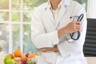 医生营养学家坐着的桌子上与水果和维生素瓶诊所健康的饮食概念营养食物处方为好健康水果医学