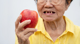 老女人穿眼镜和没有牙齿尝<strong>试吃</strong>红色的苹果概念牙科健康问题上了年纪的病人医疗和医疗保健概念