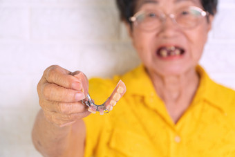 亚洲上了年纪的<strong>女人</strong>在年老持有假牙手假牙为假体设备构造取代失踪牙齿和帮助咀嚼食物的能力咀嚼食物的上了年纪的