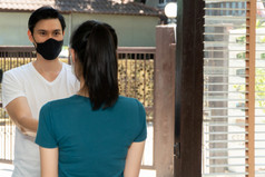 亚洲男人。穿保护面具和交付包从杂货店年轻的女客户她的首页后在线订单概念运输服务和表达交付和安全