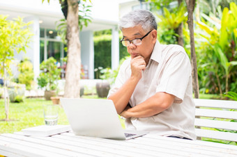 肖像老上了年纪的亚洲男人。使用电脑移动PC的后院为学习新技能后<strong>退休</strong>概念对老年人的歧视和不晚些时候为学习