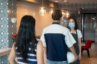 亚洲女服务员女人穿脸面具和持<strong>有</strong>红外额头温度计检查身体温度为病毒症状客户之前<strong>进</strong>入的餐厅咖啡商<strong>店</strong>