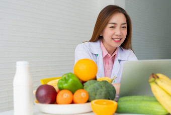 肖像亚洲微笑女营养学家<strong>打字</strong>移动PC电脑为平衡纠正饮食计划为病人重量损失建议概念健康的生活方式健康的食物节食