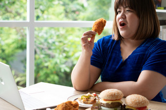 饿了超重女人持有<strong>炸鸡汉堡</strong>木板和披萨表格在工作从首页获得重量问题概念暴吃障碍床上