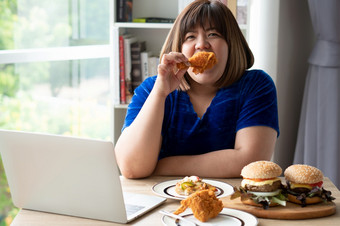 饿了超重女人持有<strong>炸鸡汉堡</strong>木板和披萨表格在工作从首页获得重量问题概念暴吃障碍床上