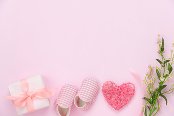 前视图空中图像装饰快乐母亲一天假期背景概念平躺礼物盒子与婴儿鞋子和爱形状花现代美丽的粉红色的纸首页办公室桌子上