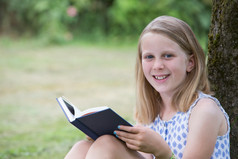 女孩坐着对树花园阅读书