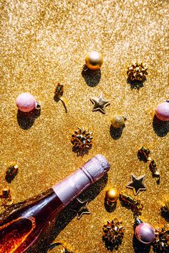 圣诞节新一年作文与瓶玫瑰香槟和金闪闪发光的装饰金闪亮的背景前视图与节日散景和阴影聚会，派对庆祝活动有创意的概念