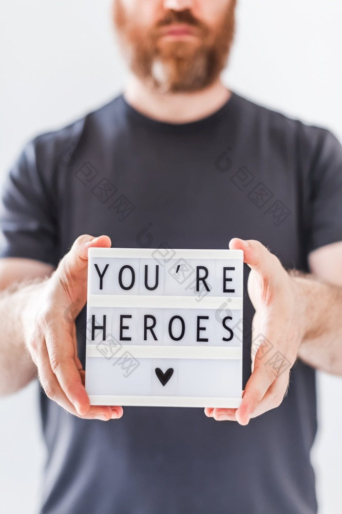 护士一天概念男人。手持有lightbox与你是英雄文本感谢医生护士和医疗工作人员工作医院在冠状病毒新冠病毒大流行
