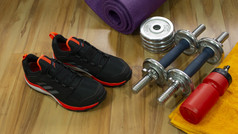 健身房集一对黑色的体育鞋子锻炼权重黄色的毛巾和红色的瓶与水木地板上集一对体育鞋子锻炼权重毛巾和瓶与水木地板上