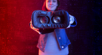 拉美裔女人显示她的虚拟现实护目镜与数字技术的前景与数字背景与蓝色的和红色的光拉美裔女人显示她的虚拟现实护目镜与数字技术的前景与蓝色的和红色的光