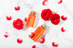 香水玫瑰水玻璃瓶和小红色的玫瑰与花瓣按摩芳香疗法和有机化妆品概念