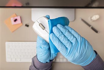 手与保护手套清洁电脑鼠标与消毒液新冠病毒冠状病毒爆发预防概念前视图