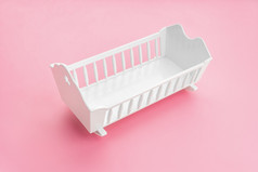 白色婴儿婴儿床孤立的粉红色的背景女孩出生率概念