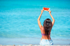 女人放松的海滩与片西瓜她的手快乐女孩有有趣的的海滩和吃西瓜