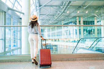 年轻的女人与行李国际机场走与她的行李航空公司乘客机场休息室等待为飞行飞机年轻的女人他与行李国际机场走与她的行李