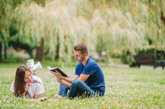 年轻的浪漫的夫妇放松的公园和读书在户外年轻的浪漫的夫妇说谎公园和阅读书