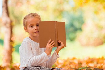 肖像可爱的小女孩在户外美丽的温暖的一天与书秋天肖像可爱的小女孩在户外美丽的秋天