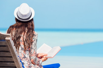 年轻的女人海滩休息室阅读书在热带白色海滩肖像年轻的女人放松的海滩阅读书