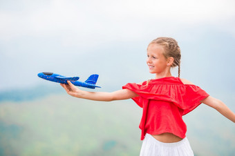可爱的女孩与小<strong>飞机玩具</strong>夏天假期山快乐小女孩与玩具飞机手山