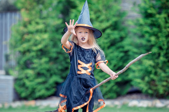 可爱的小女孩穿女巫服装万圣节秋天一天和有有趣的与扫帚在户外技巧治疗快乐女孩万圣节服装与杰克南瓜技巧治疗