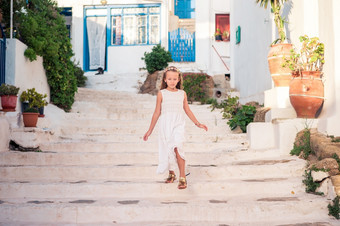 小女孩街典型的希腊传统的村与白色墙和色彩斑斓的门米克诺斯岛希腊孩子街典型的希腊传统的村与白色墙和色彩斑斓的门米克诺斯岛