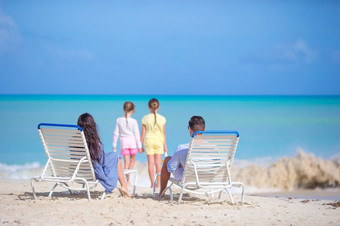 快乐美丽的家庭<strong>四个</strong>的海滩父母放松日光浴浴床和孩子们有有趣的的海滨快乐美丽的家庭<strong>四个</strong>的海滩