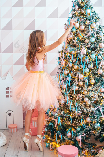 快乐圣诞节和快乐新一年可爱的小女孩装修的树在室内的早....之前圣诞节美丽的女孩附近圣诞节树装修
