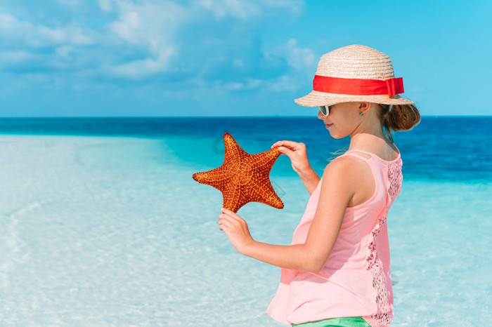 小女孩他与海星的热带海滩可爱的小女孩与海