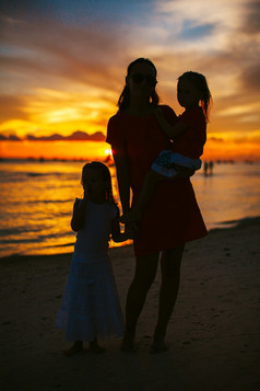 年轻的美丽的妈妈。和她的可爱的小女儿的海滩日落美丽的妈妈。和女儿的海滩享受日落视图