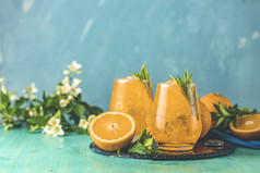 两个眼镜橙色冰喝与新鲜的薄荷木绿松石表格表面新鲜的鸡尾酒饮料与冰水果和草装饰含酒精的不含酒精的饮料夏天新鲜的喝