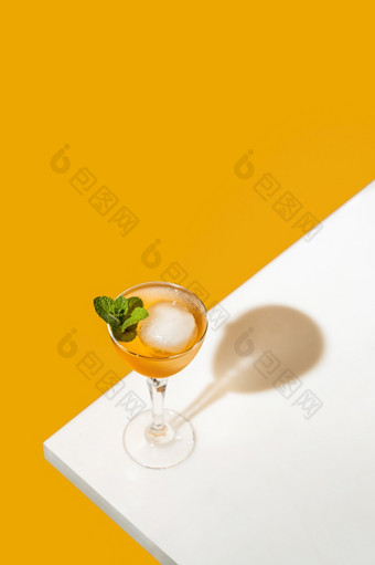 优雅的高脚杯子玻璃新鲜的橙色鸡尾酒与大冰球白色表格表面明亮的黄色的<strong>背景</strong>春天夏天艺术喝食物概念