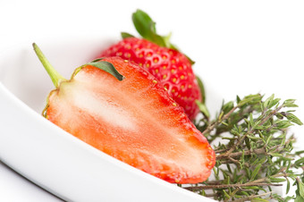 减少了一半新鲜的多汁的成熟的红色的草莓显示的结构的肉纸浆白色碗与用钉子钉上新鲜的迷迭香使用芳香调味料调味料而且烹饪成分