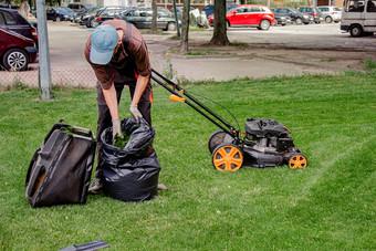 割草家庭花园草坪上与黑色的袋草剪报工人收集割草草黑色的塑料袋最近修剪草坪上割草家庭花园草坪上与黑色的袋草剪报