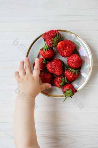 手孩子与草莓乡村背景板草莓的概念夏天健康的吃视图从以上公寓手孩子与草莓乡村背景板草莓