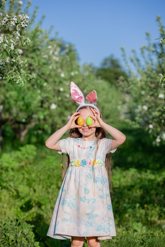 可爱的女孩与兔子耳朵复活节一天女孩追逐复活节鸡蛋的花园的女孩有篮子与画鸡蛋可爱的女孩与兔子耳朵复活节一天女孩追逐复活节鸡蛋的花园