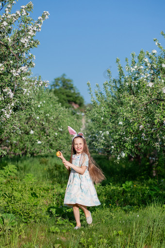 可爱的女孩与兔子耳朵复活节一天女孩追逐复活节鸡蛋的花园的女孩有篮子与画鸡蛋可爱的女孩与兔子耳朵复活节一天女孩追逐复活节鸡蛋的花园