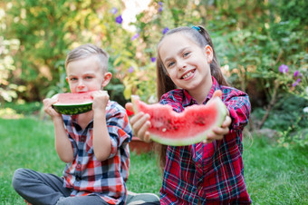 快乐孩子们吃西瓜的花园孩子们吃水果在户外健康的零食为孩子们小女孩和男孩玩的花园咬片水瓜快乐孩子们吃西瓜的花园孩子们吃水果在户外小女孩和男孩玩的花园咬片水瓜