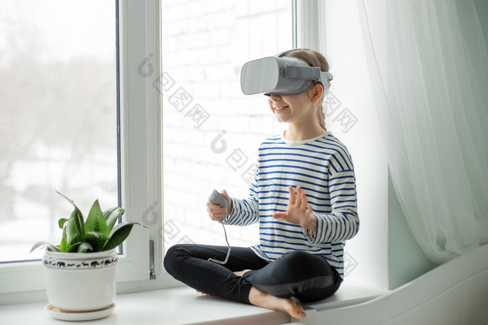 孩子与虚拟现实耳机坐着的表格在室内首页女孩探索的世界虚拟现实通过视频和游戏技术的未来孩子与虚拟现实耳机坐着的表格在室内首页女孩探索的世界虚拟现实通过视频和游戏