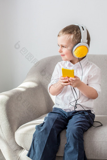 <strong>男孩听音乐</strong>与耳机坐着的沙发上<strong>男孩听音乐</strong>