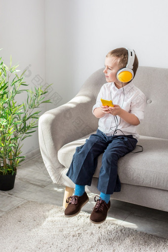 男孩听音乐与耳机坐着的沙发上男孩听音乐