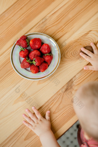 手孩子与草莓乡村背景板草莓的概念夏天健康的吃视图从以上公寓手孩子与草莓乡村背景板草莓