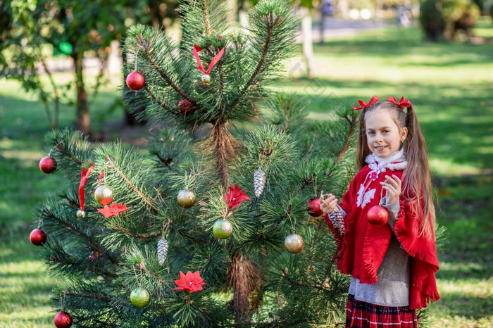 可爱的女孩装修的圣诞节树在户外的院子里之前的假期快乐圣诞节和快乐假期可爱的女孩装修的圣诞节树在户外的院子里之前的假期