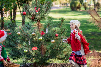 可爱的女孩<strong>装修</strong>的圣诞节树在户外的院子里之前的假期快乐圣诞节和快乐假期可爱的女孩<strong>装修</strong>的圣诞节树在户外的院子里之前的假期