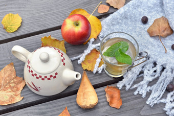 薄荷杯茶木表格花园与茶壶在秋天的叶和红色的苹果<strong>羊毛</strong>围巾
