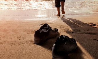 工作生活平衡概念商人取从他的工作鞋子和离开的沙子海滩为走成的海阳光明媚的一天低角视图相当工作离开从硬工作和责任