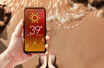 高温度天气预测显示移动屏幕热夏天阳光明媚的一天技术为生态概念沙子海滩与阳光背景前视图
